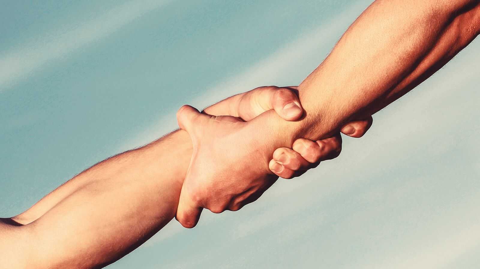 Helping hands concept, support. Close up help arm and international day of peace, support. Hands of on blue sky background.